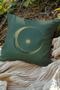 Emerald green throw pillow cover featuring a golden crescent moon and sun design with radiating lines, perfect for celestial or bohemian decor themes.